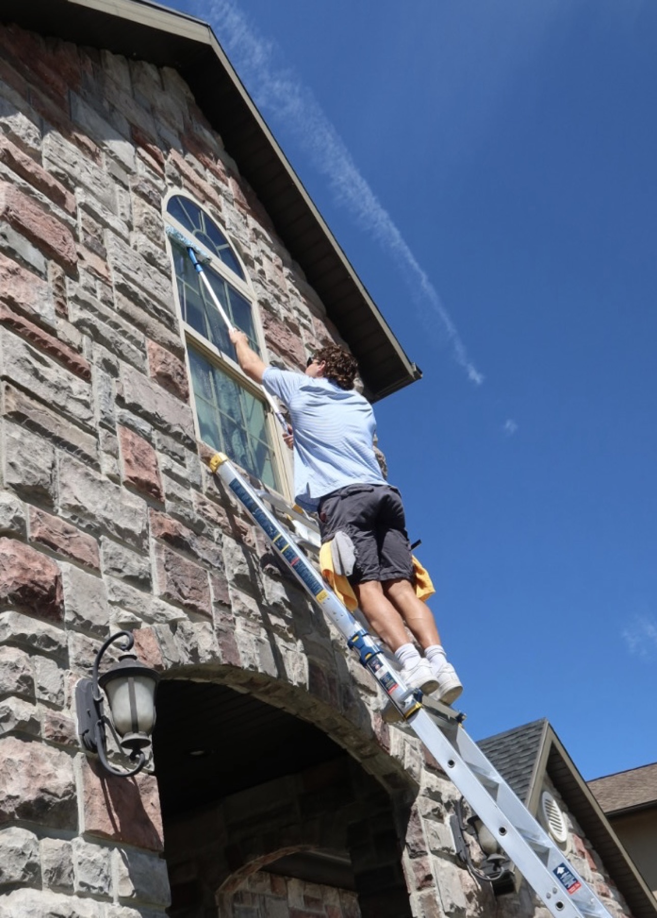 Trevor cleaning a second-story exterior window